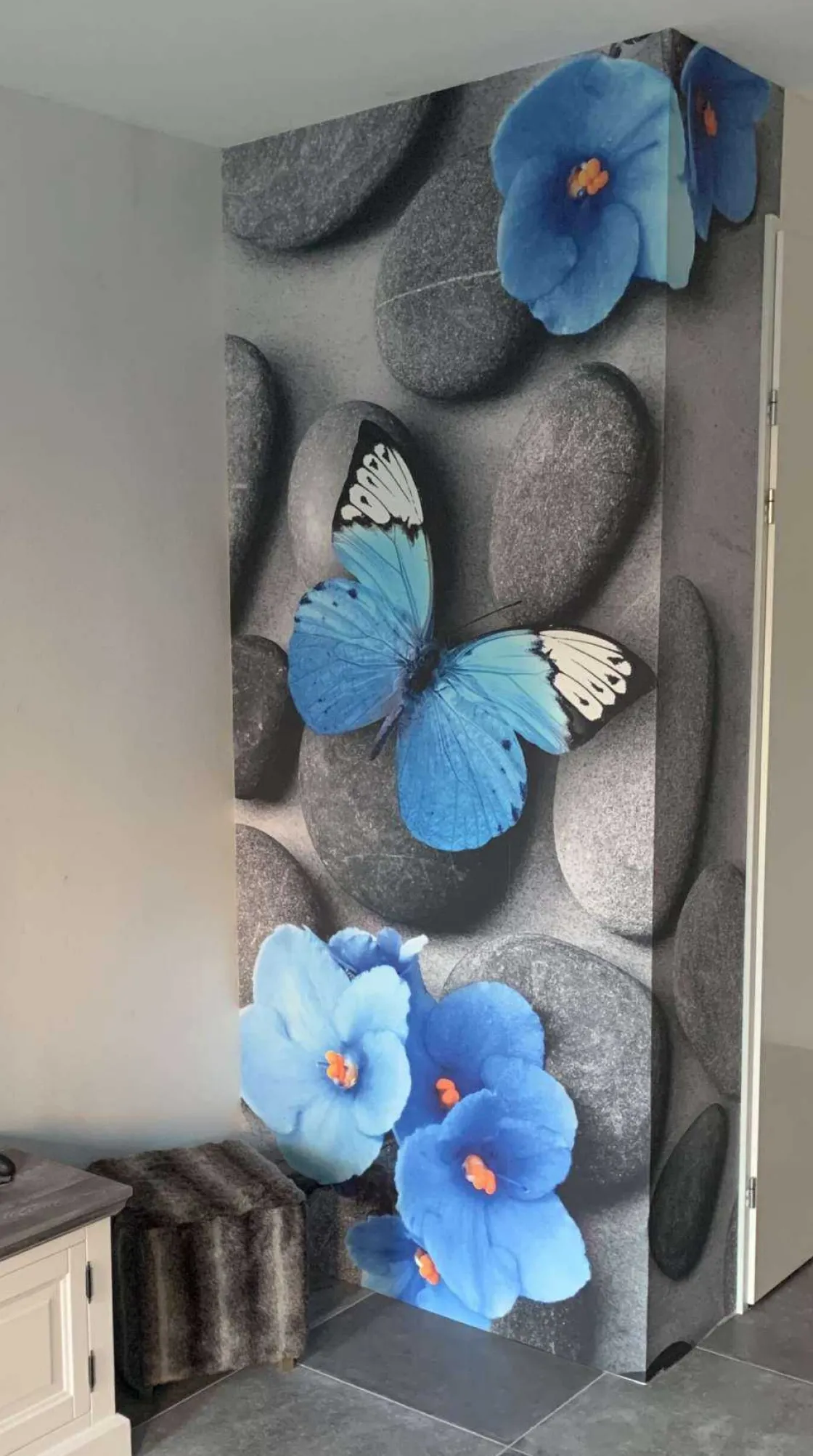 grijze_stenen_met_een_bla_1.webp Clearance Grijze stenen met een blauwe vlinder en bloemen fotobehang Oppervlakten | Bloemen